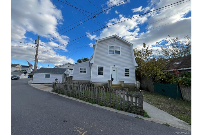 Dutch colonial featuring a fenced front yard and a gambrel roof
