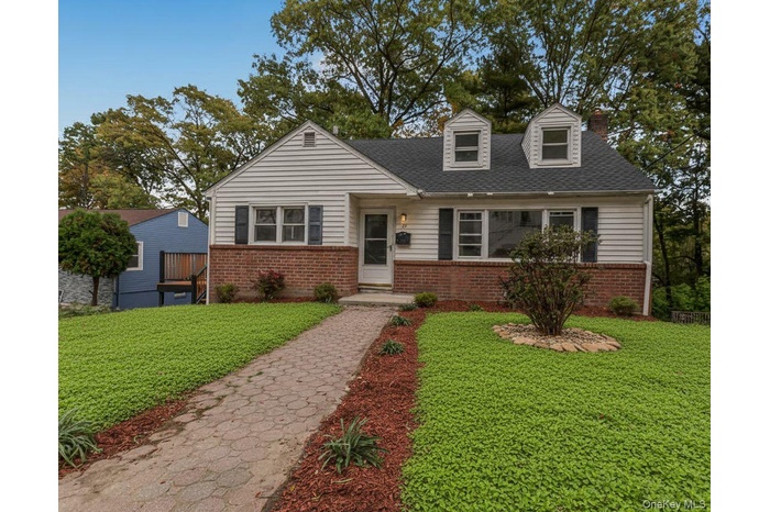 View of front of home featuring a front lawn, brick siding, and roof with shingles