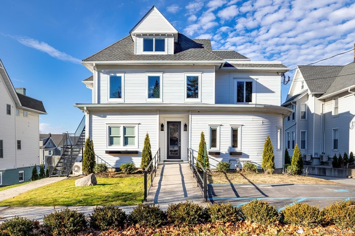 American foursquare style home featuring stairs, roof with shingles, and a front yard
