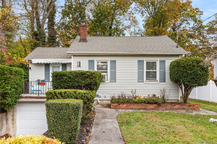 View of front of home with a chimney, roof with shingles, and an attached garage