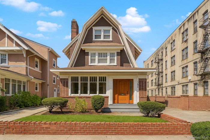 View of front of house featuring brick siding, a chimney, and roof with shingles