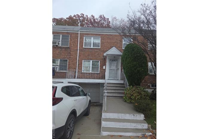 View of front of home with brick siding, driveway, an attached garage, and roof with shingles