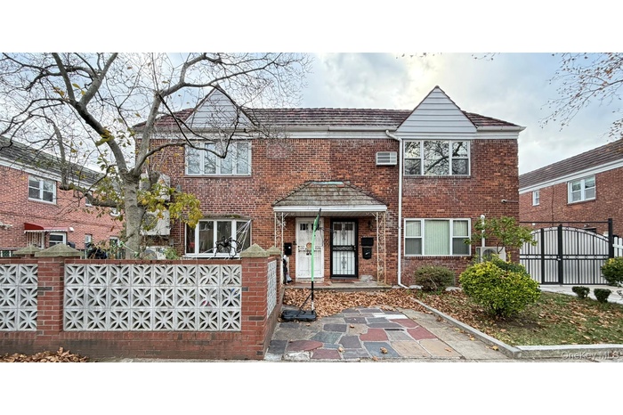 Traditional-style house featuring a gate, a fenced front yard, and brick siding