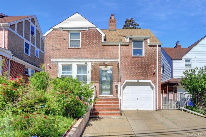 View of front of home with brick siding, concrete driveway, a chimney, an attached garage, and roof with shingles