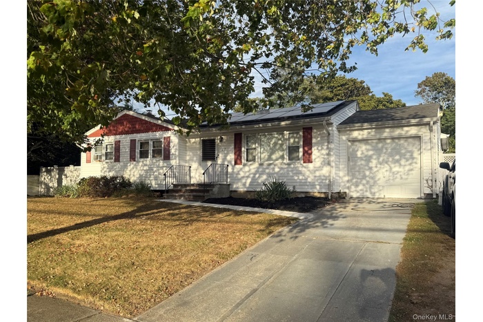 Ranch-style home featuring roof mounted solar panels, driveway, a front yard, and an attached garage