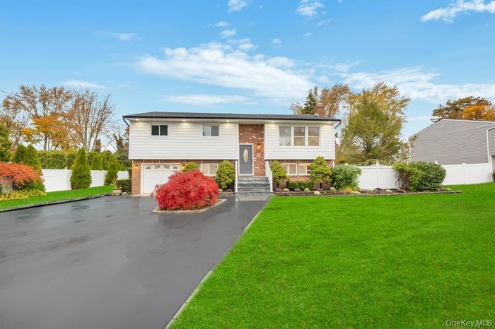 Split foyer home with brick siding, asphalt driveway, an attached garage, and a chimney