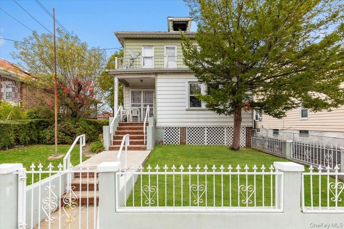 View of front of house with a fenced front yard, a gate, and a balcony