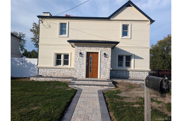 View of front of property featuring stone siding, stucco siding, and a gate