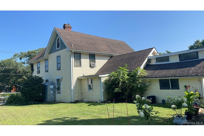 Rear view of property with roof with shingles, a yard, and a chimney