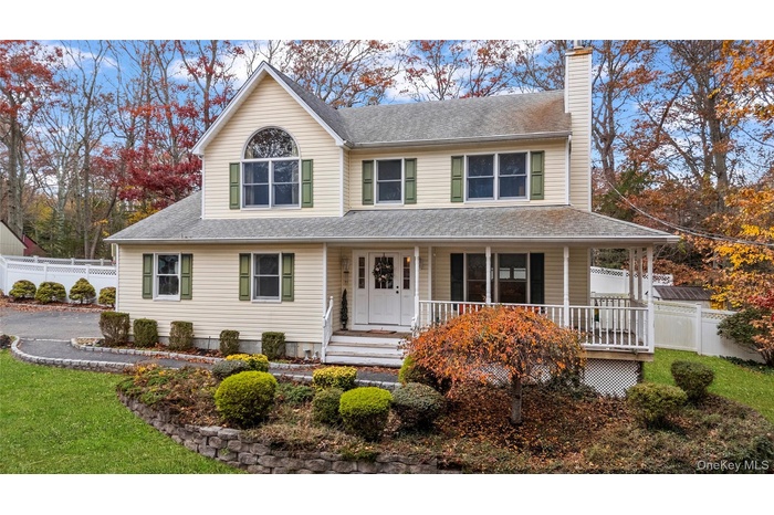 View of front of property featuring a chimney, a porch, and a shingled roof