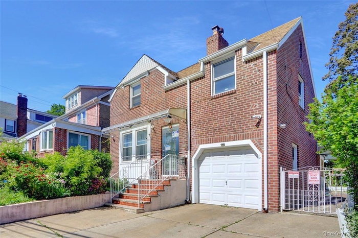 Traditional-style home with an attached garage, brick siding, a chimney, and driveway