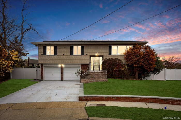 Split foyer home with a gate, concrete driveway, a garage, and brick siding
