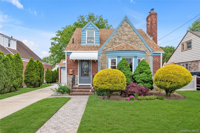 View of front of house with a front lawn, roof with shingles, and brick siding