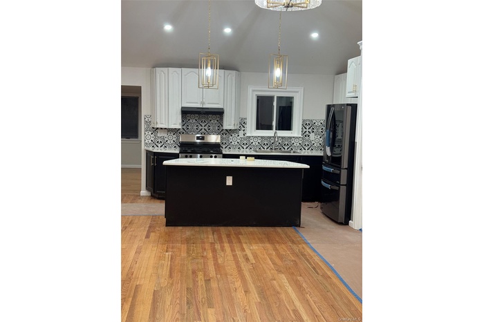 Kitchen featuring dark cabinetry, decorative backsplash, white cabinetry, decorative light fixtures, and recessed lighting