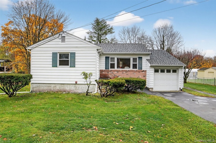 Single story home with a front yard, a shingled roof, brick siding, and a garage
