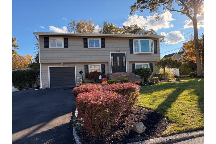Bi-level home with asphalt driveway, a front lawn, and a garage