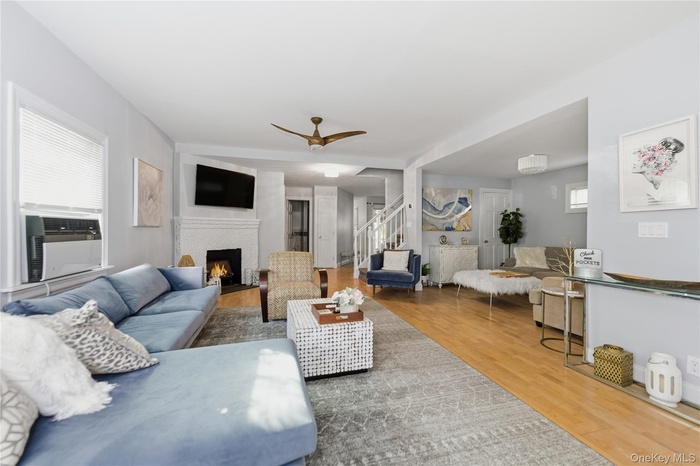 Living area with wood finished floors, ceiling fan, stairway, a brick fireplace