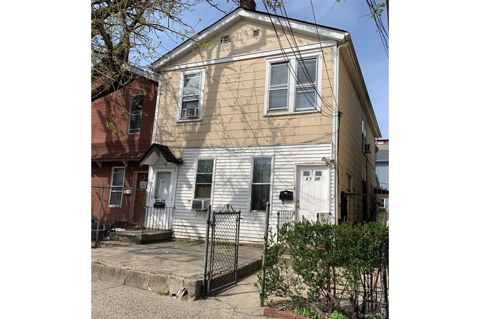 View of front facade featuring a gate, a chimney, and cooling unit
