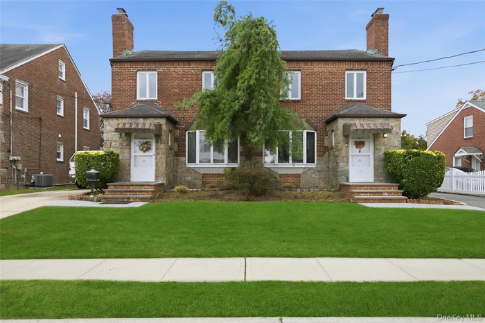 View of front facade with a chimney, stone siding, and brick siding