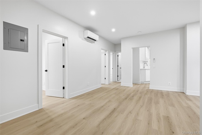 Unfurnished living room with electric panel, light wood-style floors, and recessed lighting