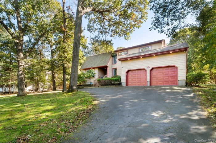 View of front of property featuring driveway, a front yard, and a shingled roof