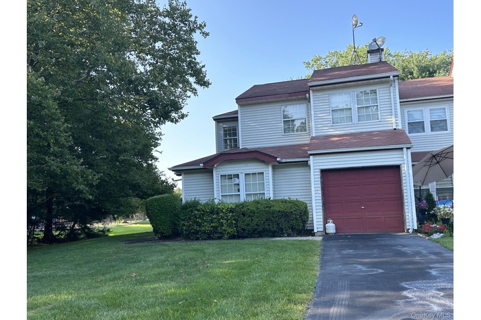 Traditional home with a front lawn, driveway, a chimney, and a garage