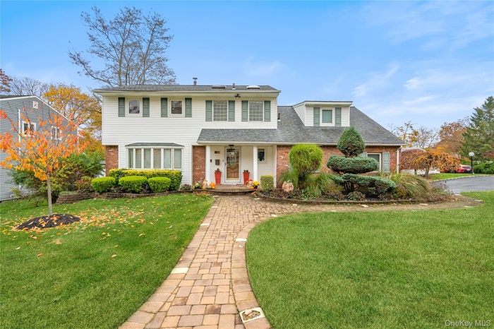View of front of house with brick siding, a front lawn, and roof with shingles