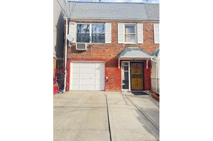 View of front facade with a shingled roof, brick siding, and driveway