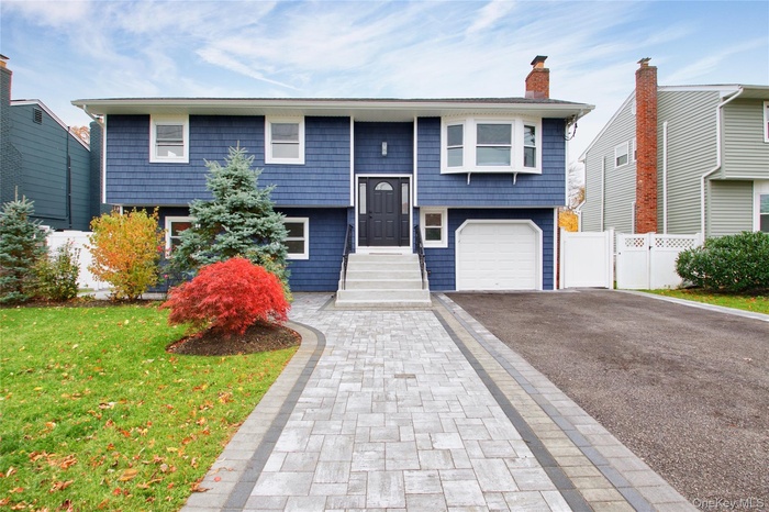 Bi-level home featuring asphalt driveway and a chimney