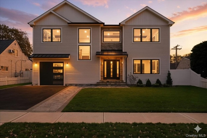 Modern home featuring a metal roof, a standing seam roof, asphalt driveway, and board and batten siding