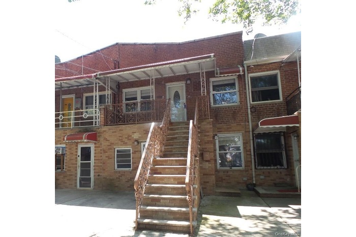 View of front facade featuring a balcony, brick siding, and stairs
