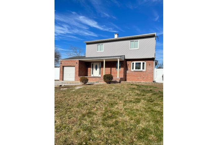 Traditional home featuring a porch, a garage, brick siding, and a chimney