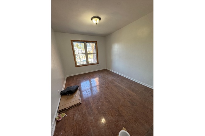 Unfurnished room featuring baseboards and dark wood-style floors