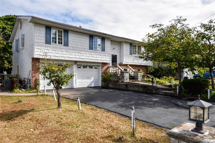 Raised ranch with brick siding, asphalt driveway, and a garage