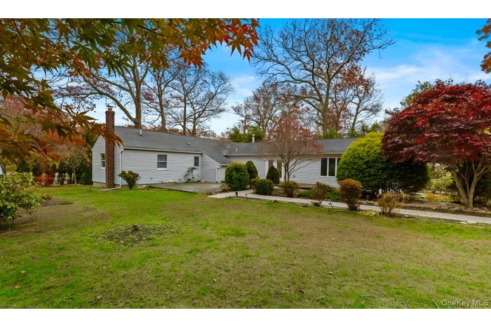Back of house with a lawn, a patio, and a chimney