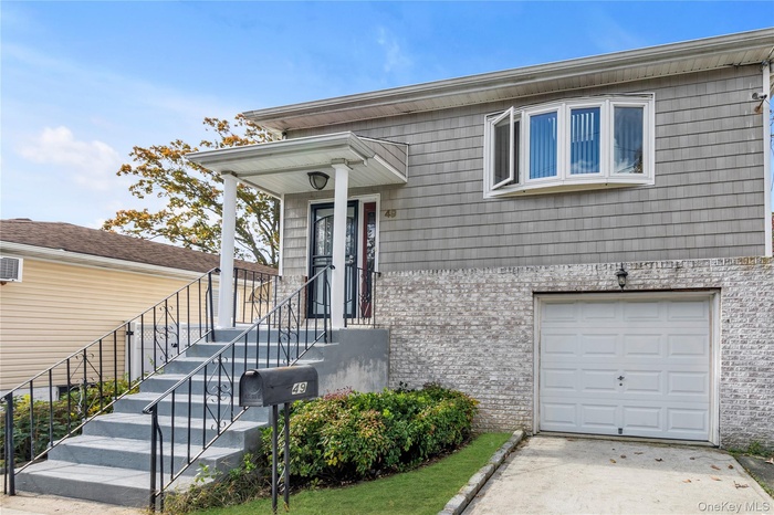 View of front of home with brick siding, an AC wall unit, and an attached garage