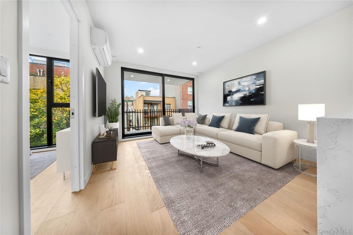 Living area with healthy amount of natural light, an AC wall unit, light wood-style floors, recessed lighting, and floor to ceiling windows