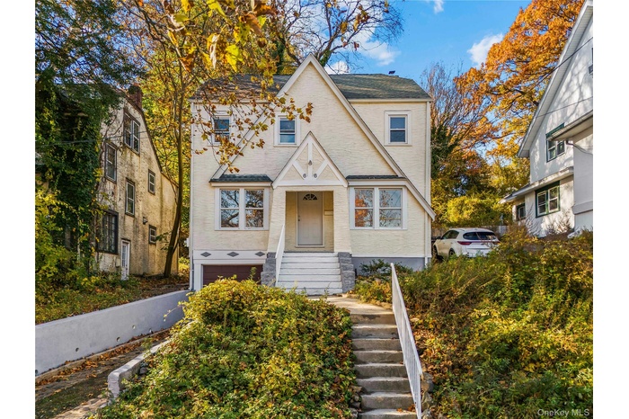 View of front facade featuring stairway, roof with shingles, and an attached garage