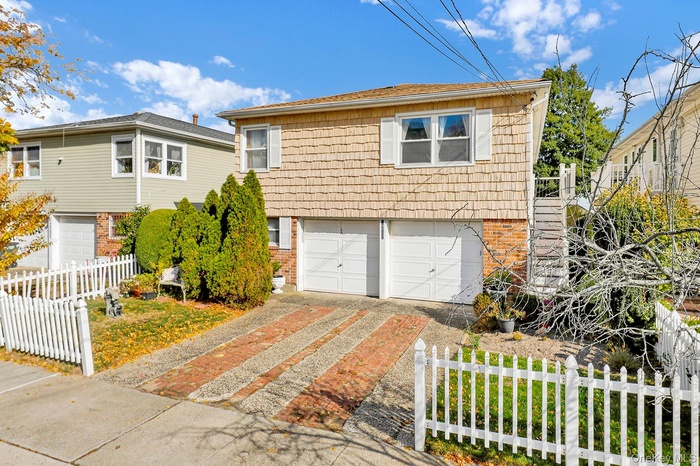 View of front facade featuring driveway, an attached garage, and brick siding