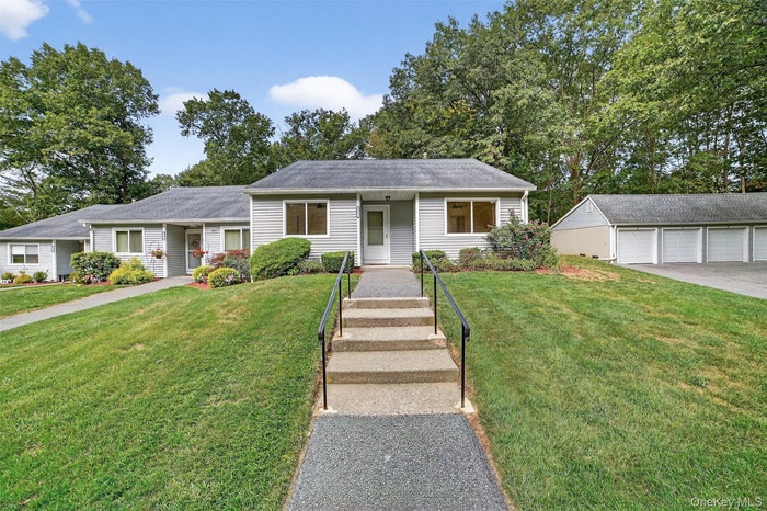 View of front facade featuring an outbuilding, a front lawn, and a garage