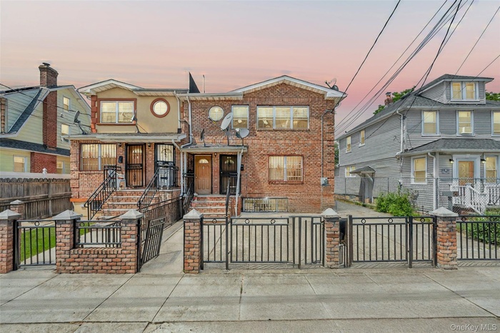 View of front of property featuring a gate, a fenced front yard, and brick siding