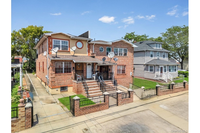 View of front facade featuring a gate, a fenced front yard, brick siding, and a porch
