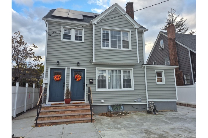 View of front of property with solar panels, a chimney, and entry steps