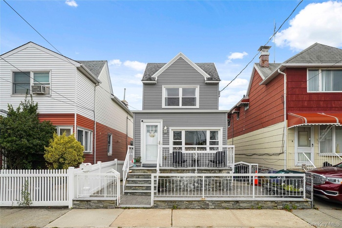 Traditional home featuring a fenced front yard, a gate, and roof with shingles