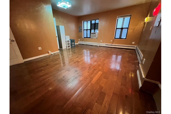 Unfurnished living room with dark wood-style flooring, a baseboard radiator, and cooling unit
