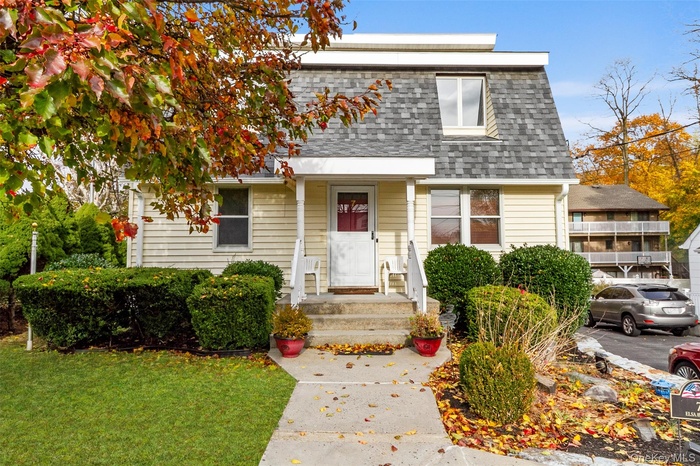 View of front of home with roof with shingles, a front lawn, and mansard roof