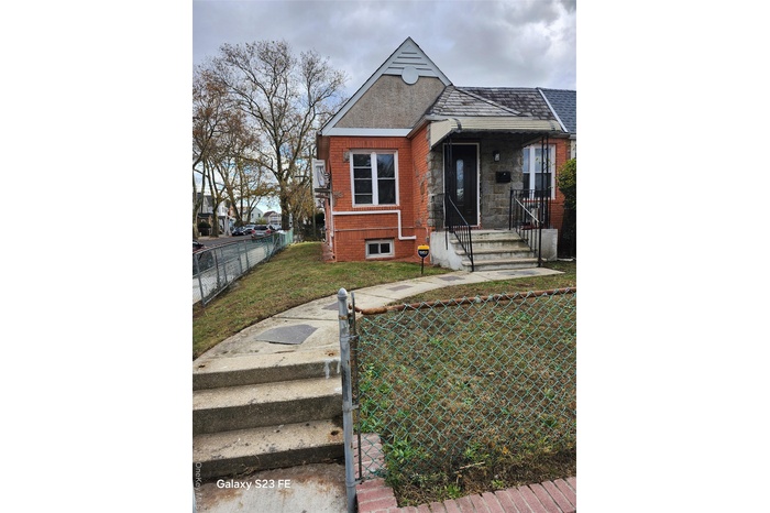 View of front of house featuring a fenced front yard, brick siding, a gate, and covered porch