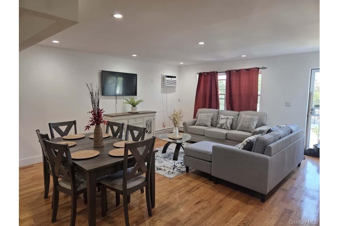 Living room with light wood-style flooring, recessed lighting, and a wall mounted AC