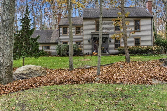View of front of property with a chimney, a front yard, and roof with shingles