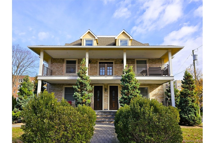View of front facade featuring roof with shingles and a porch